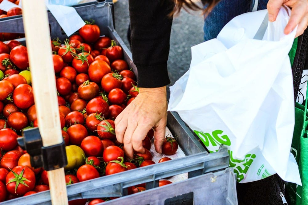 mano cogiendo tomates en un mercado